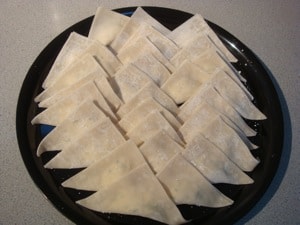 Triangle wontons on black plate before steamed 