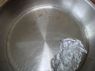 Stainless steel pan with vinegar and crumpled aluminum foil