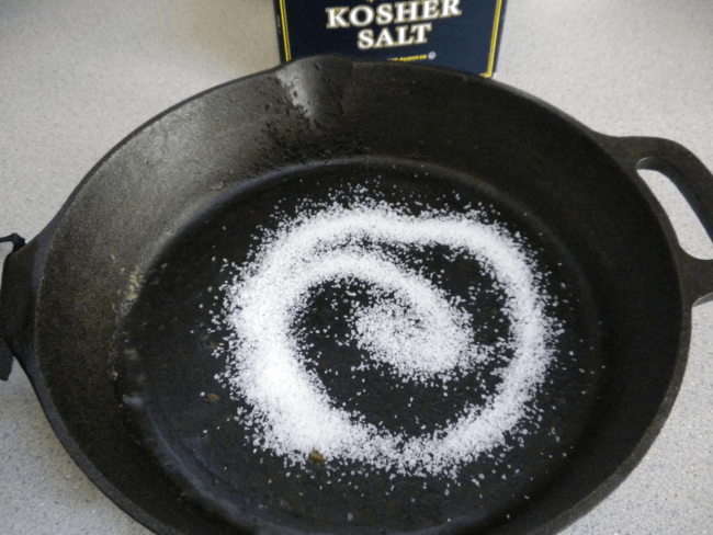 kosher salt box behind cast iron with kosher salt sprinkled in center