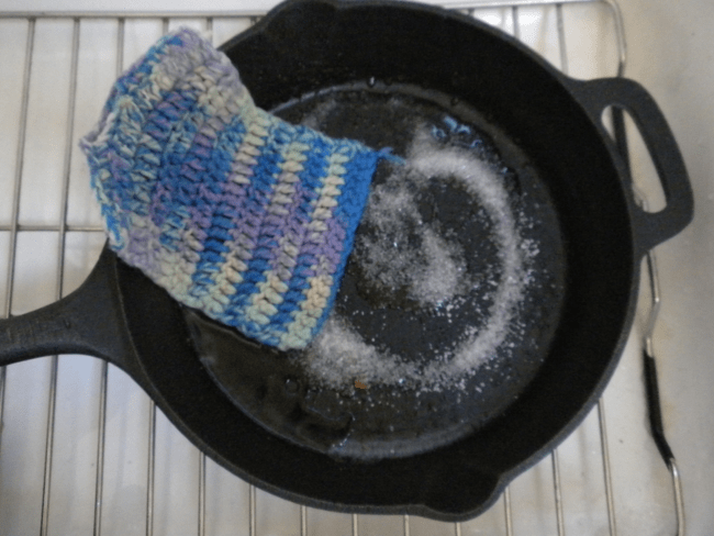cast iron pan with salt in it and a dish washing cloth 