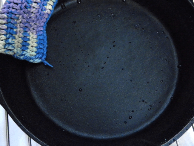 Clean cast iron pan with dishwashing cloth hanging over it