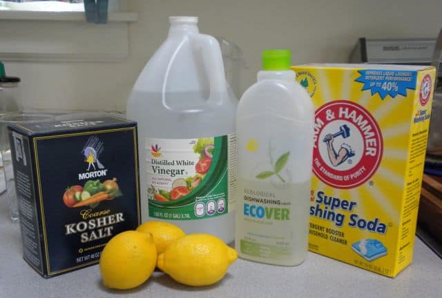 kosher salt next to white vinegar, dishwashing soap, washing soda, and lemons