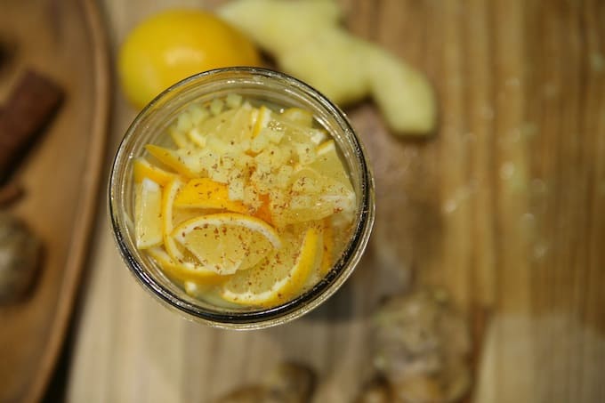layered sliced lemon and grated ginger in mason jar with honey and cinnamon