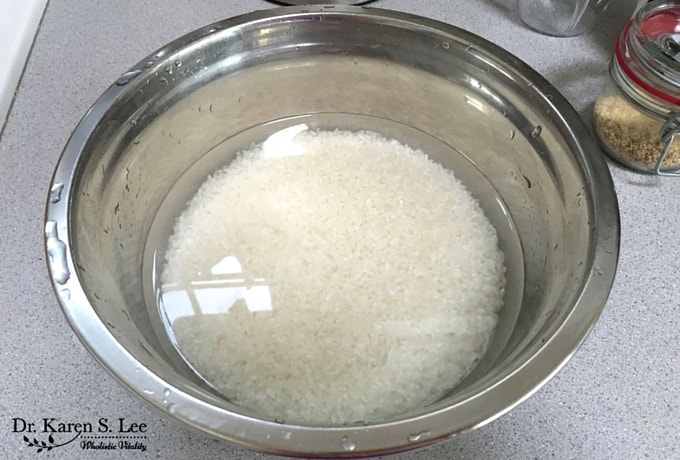 white rice soaking in water in a stainless steel bowl