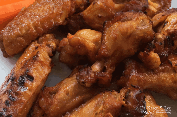 Chicken wings next to carrots on white plate