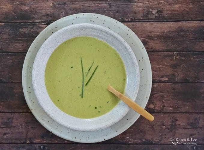 dairy-free Creamy Roasted Asparagus Soup in white bowl with wooden spoon in soup