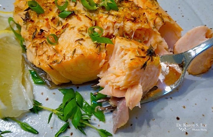 Toasted Coconut Salmon with scallion garnish on a fork next to lemon wedge