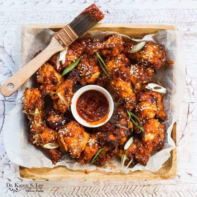 red gochujang coated chicken wings in a basket with a brush resting over the basket