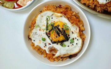 White bowl of kimchi pork fried rice on a white table