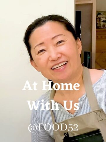 smiling asian woman wearing grey striped shirt with beige apron