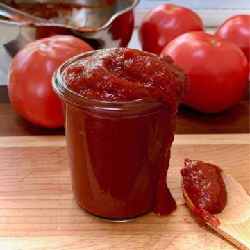 Ketchup in a glass bottle on wooden cutting board