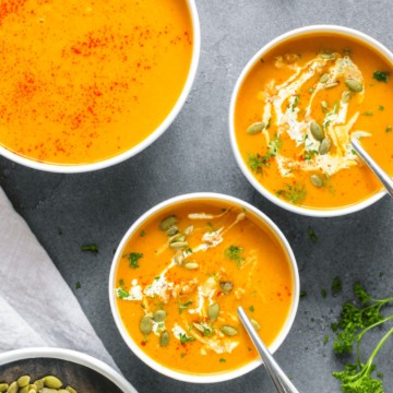 3 bowls of squash soup against grey background