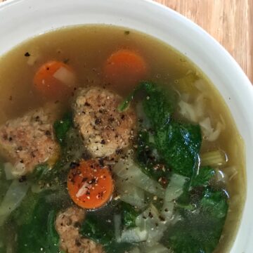 meatballs, carrots, green vegetable soup in white bowl