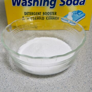 white powder in glass bowl on grey counter washing soda box in back