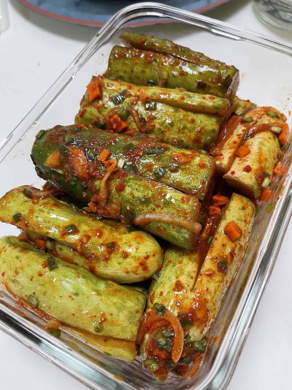 cucumbers stuffed with red pepper flakes, carrots, and onions in a glass container